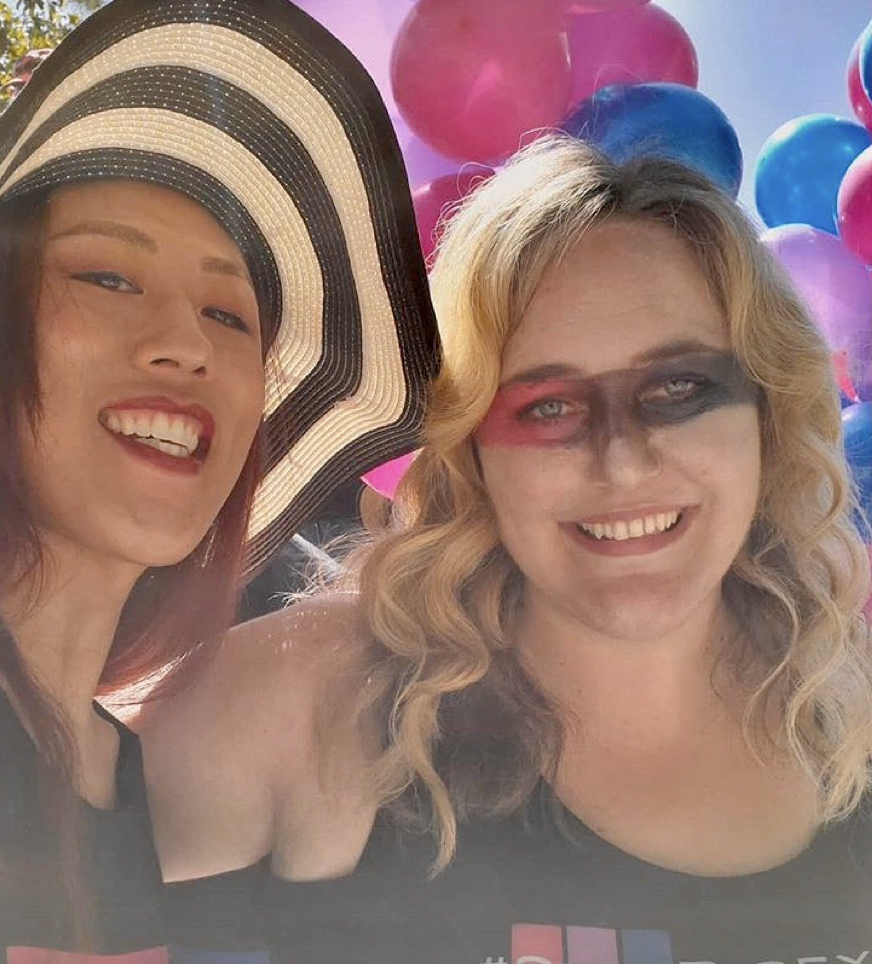 Nicky and Jennie a site author smiling and wearing bi pride colors at bi parade.