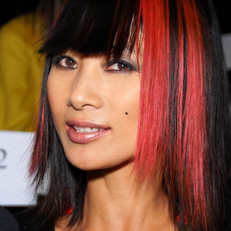 Mai Ling posing at a carpet event with dyed red hair.