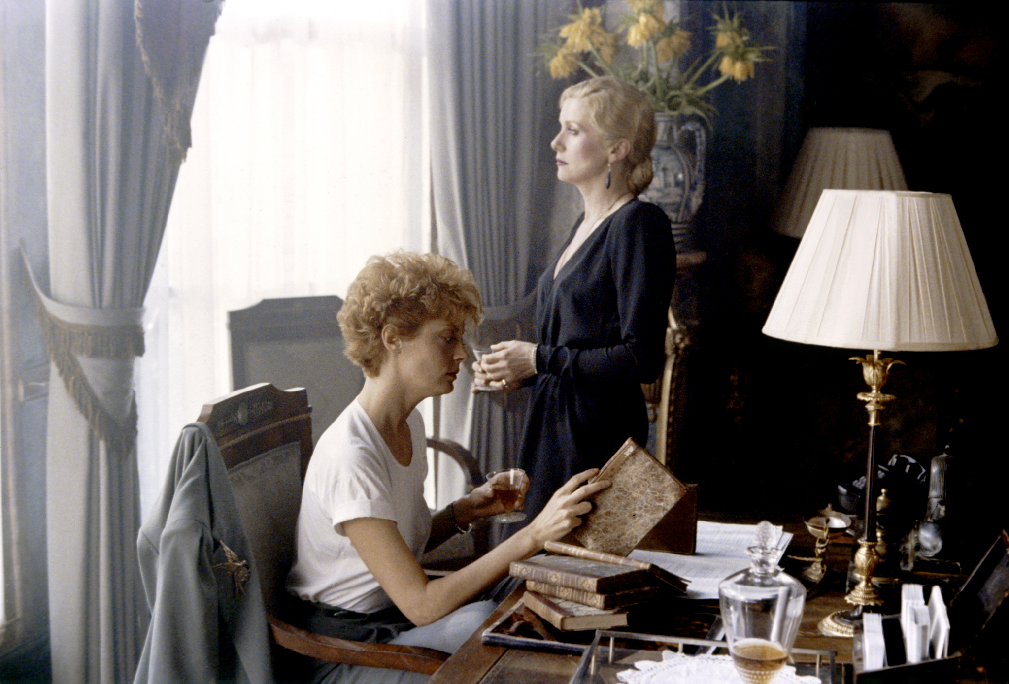 Catherine y Susan en un estudio, mirando notas mientras Catherine mira por la ventana.