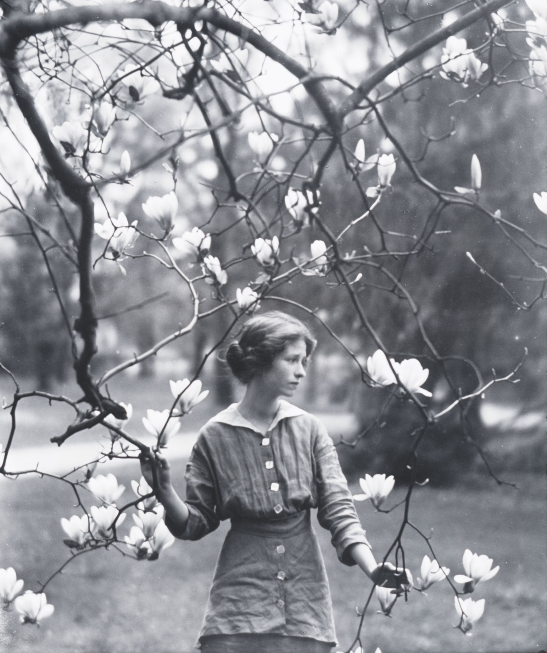 Edna St. Vincent en el campo rodeada de un arbol con flores.
