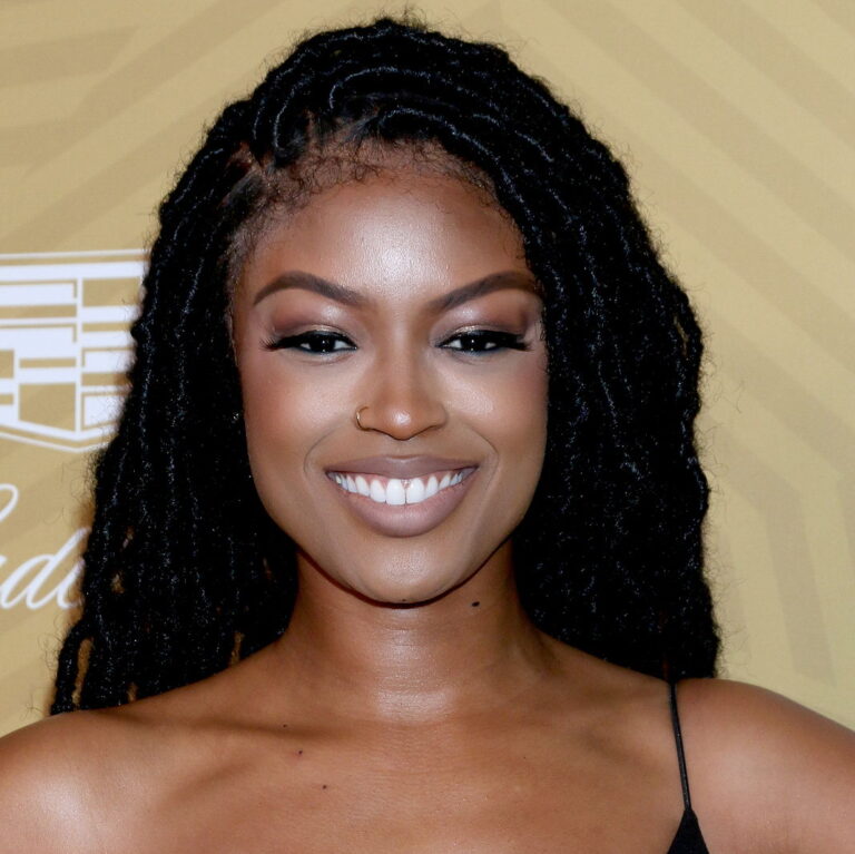 Javicia Leslie smiling and posing for the camera with a small black dress during a carpet event
