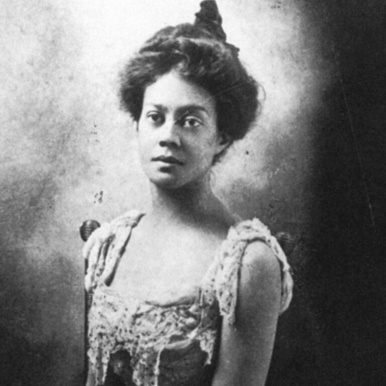 Black and white image of a young Alice Dunbar with her hair up and a dress, posing for a portrait with a straight face.