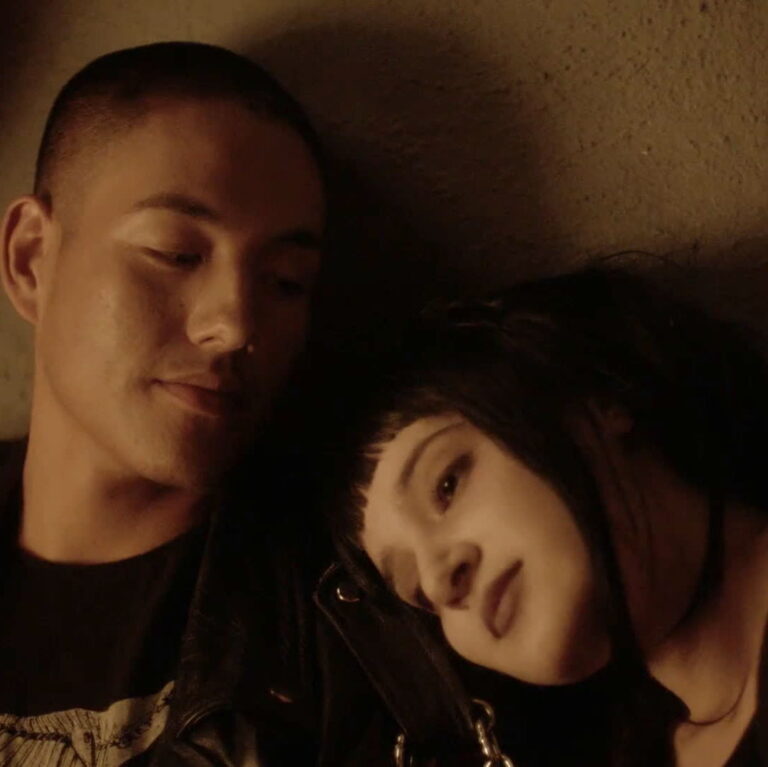 Joey lays her head on Victor's shoulder who is smiling looking at her.