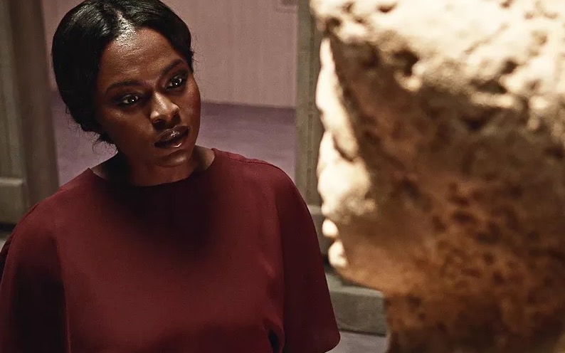 Bilquis staring intently at the head of a statue.