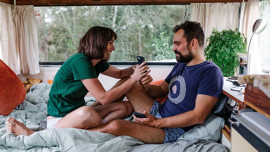 Zoe and Lucks sitting in bed in their underwear looking at something on Zoes phone.