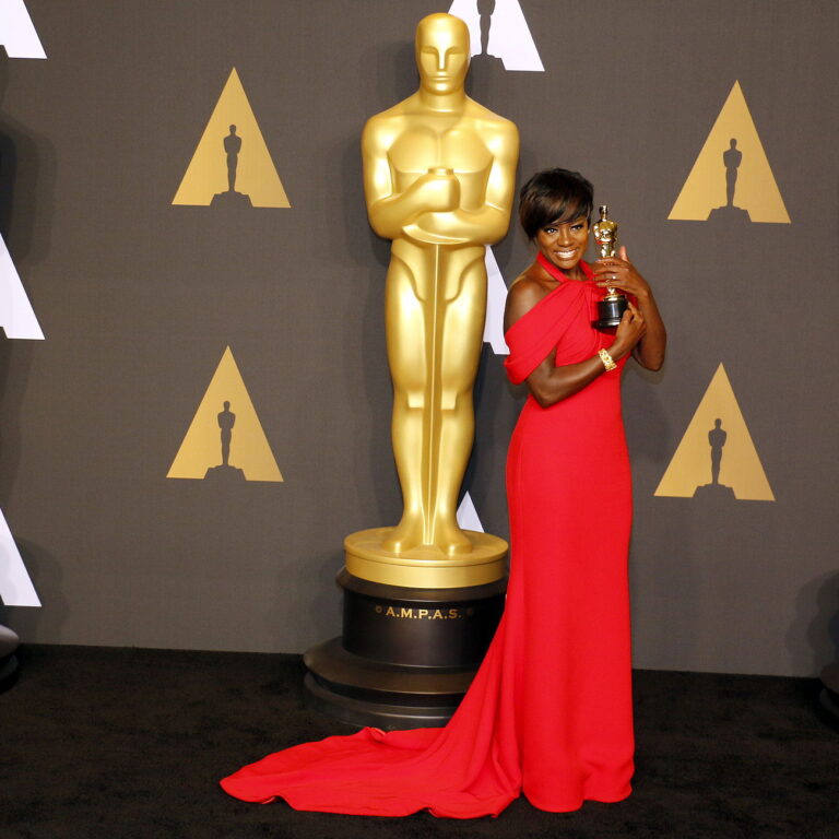 Viola Davis receiving an oscar award with a long red dress