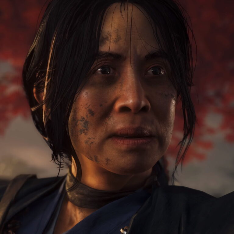 Lady Masako looking intently in front with a red tree in the background. Her face is covered in mud.