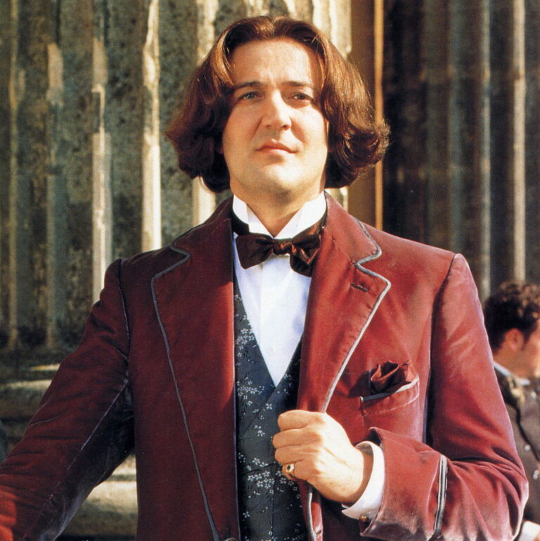 Oscar Wilde wearing a victorian era suit with long hair.