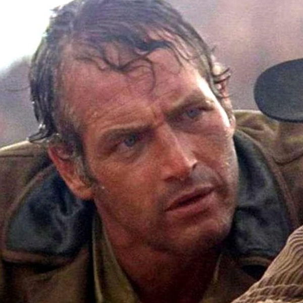 Image of Butch Cassidy under rain looking intently to the side.