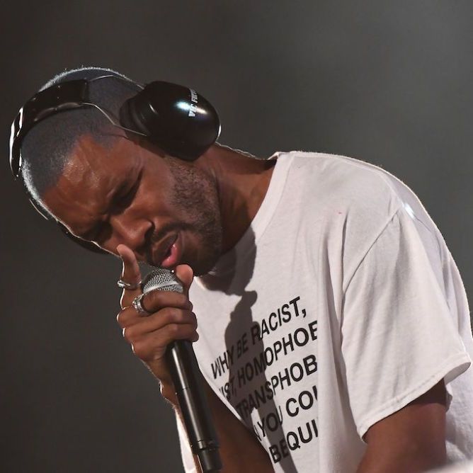 Image of Frank Ocean performing at a concert, singing intensely into the mic while his eyes are closed.