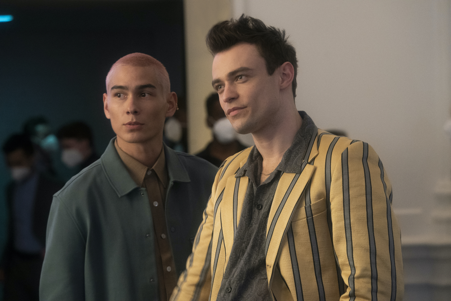 Max and Aki wearing stylish outfits standing next to eachother and looking to someone off camera.