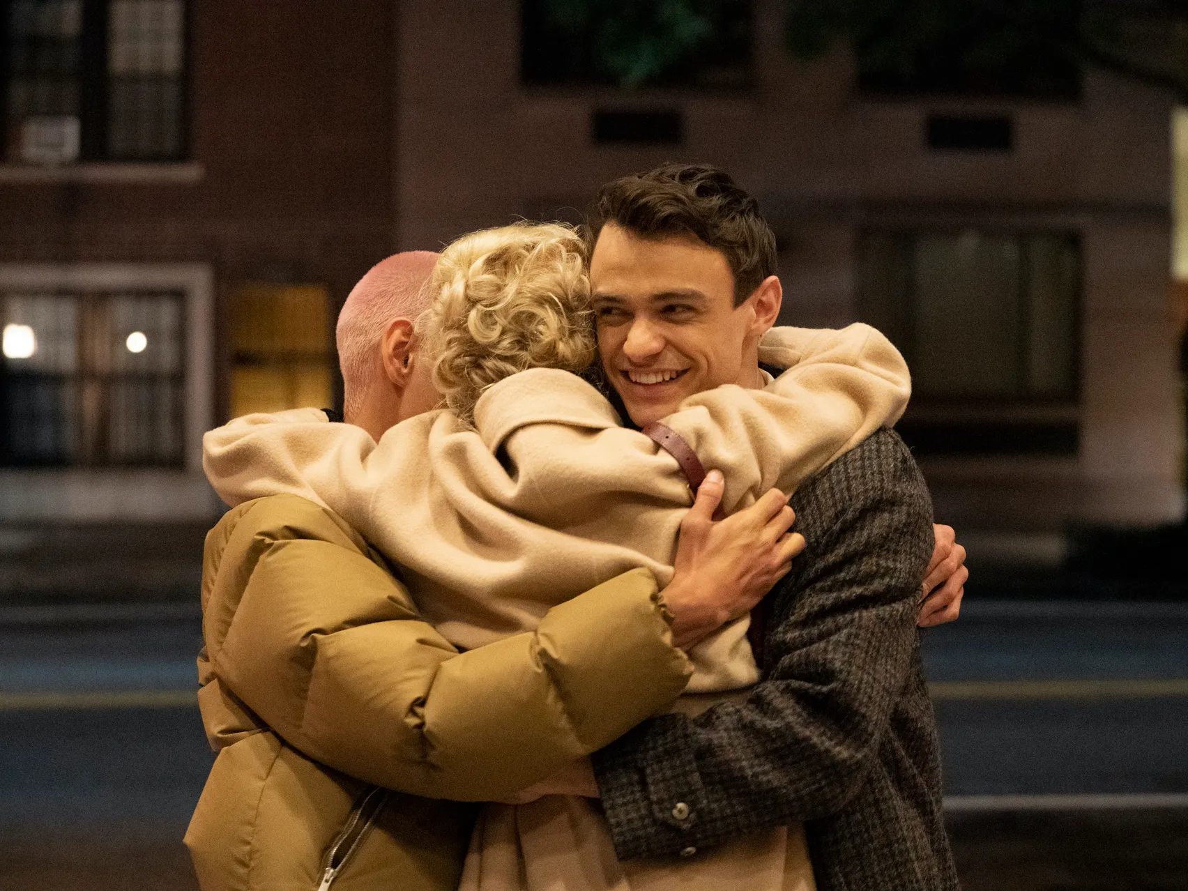 Gossip Girl characters Aki, Audrey, and Max hugging and smiling