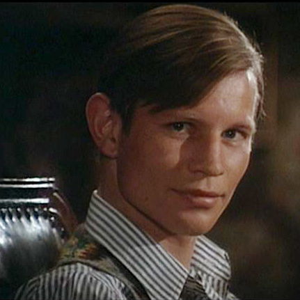 Bryan smiling and looking at the camera, sitting in a black chair and a button up shirt.