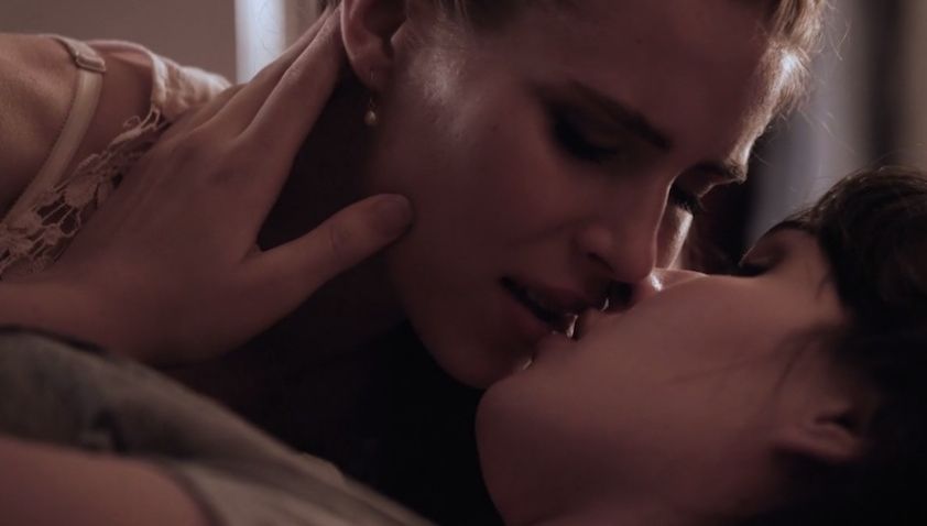 Close up of Ricky and Francesca laying down together and kissing with their eyes closed.