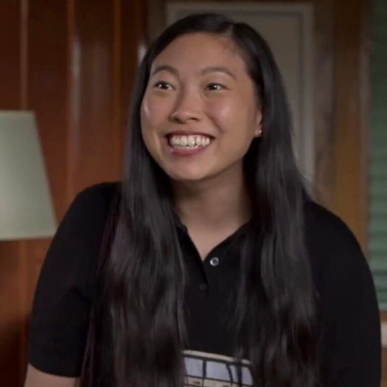 Nora wearing a polo shirt is smiling big for someone off camera.