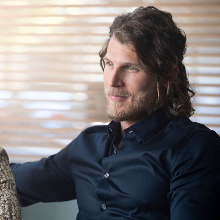 Cary Conrad sitting on a booth at a restaurant smirking with his wife next to him.