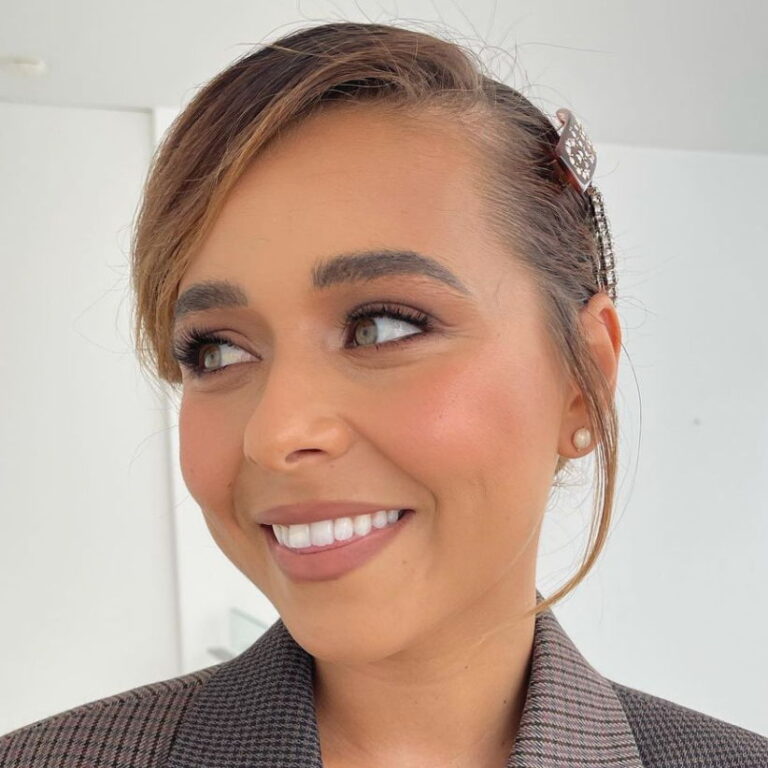 Brooke wearing a blazer smiles and looks to the side.