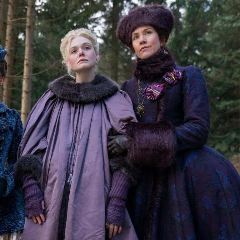 Elizabeth holding a distressed Catherine. Both are wearing purple dresses with warm clothing in the woods.