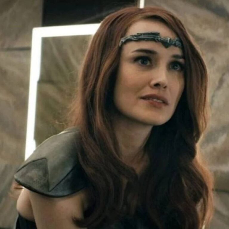 Queen Maeve smiling and looking at someone away from camera. She is wearing her tiara and hero outfit.