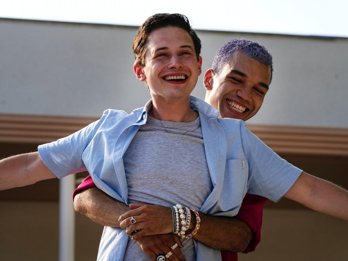 Chester abrazando a Nathan por detr&aacute;s mientras Nathan estira los brazos. Ambos se est&aacute;n riendo.