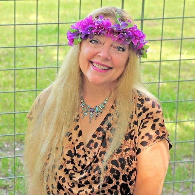 Carole wearing a flower tiara and leopard print shirt smiling.