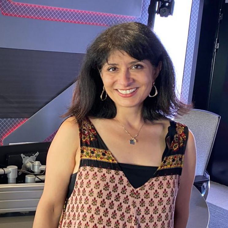 Shappi Khorsandi smiling at a radio host studio.