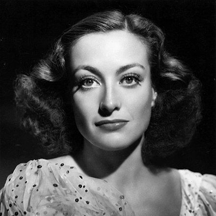 A black and white image of Joan, wearing a dress and smiling calmly.