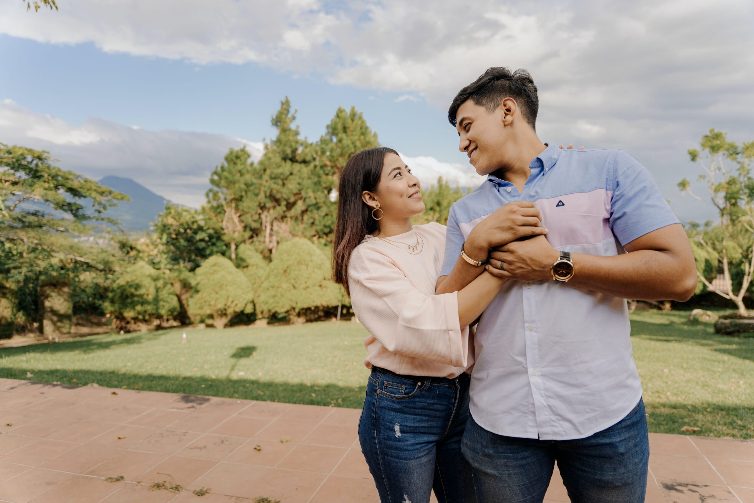 A young latin couple has an intimate moment holding onto eachother in the outdoors.