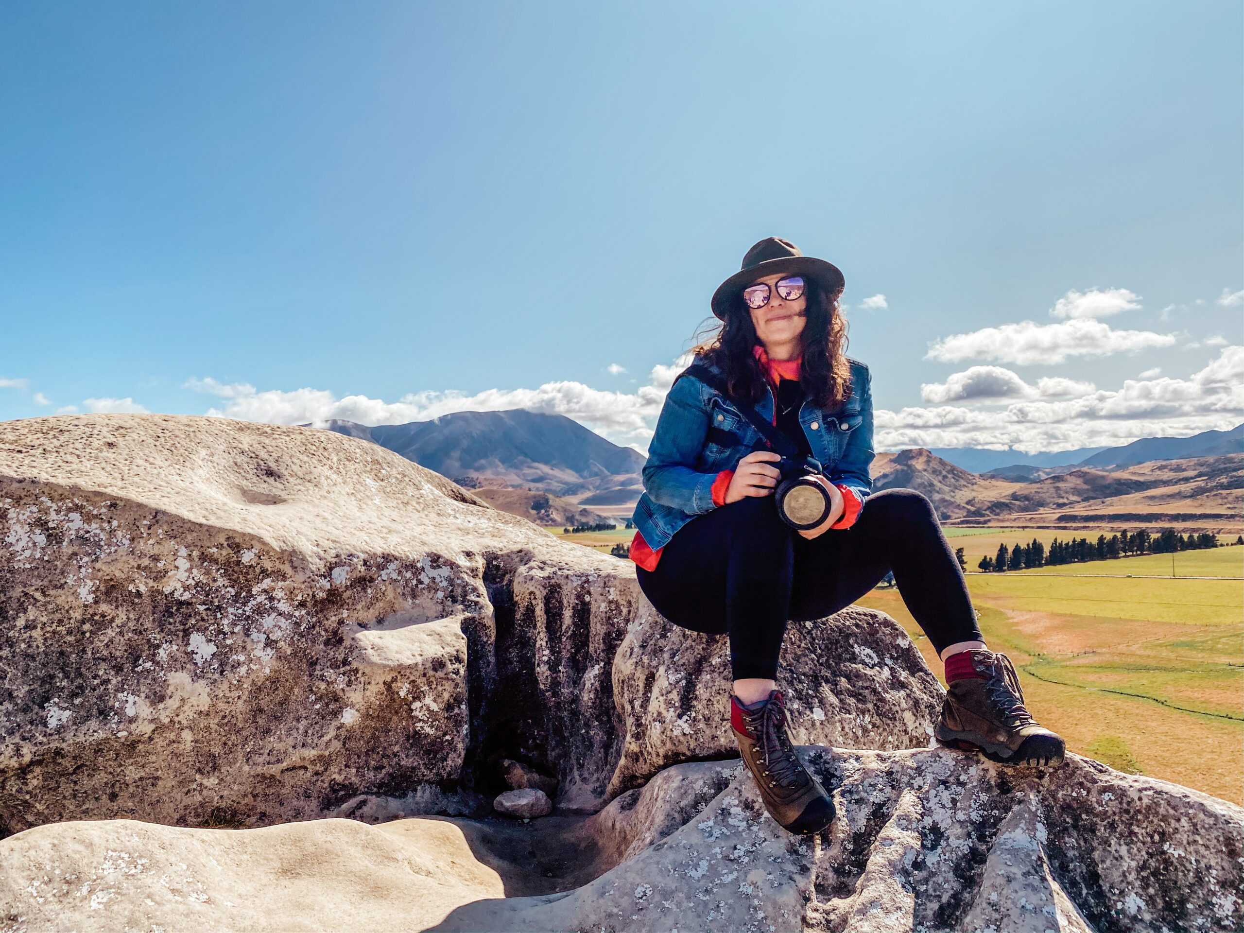 Becca sitting on top of large rocks holding her camera in a national park.