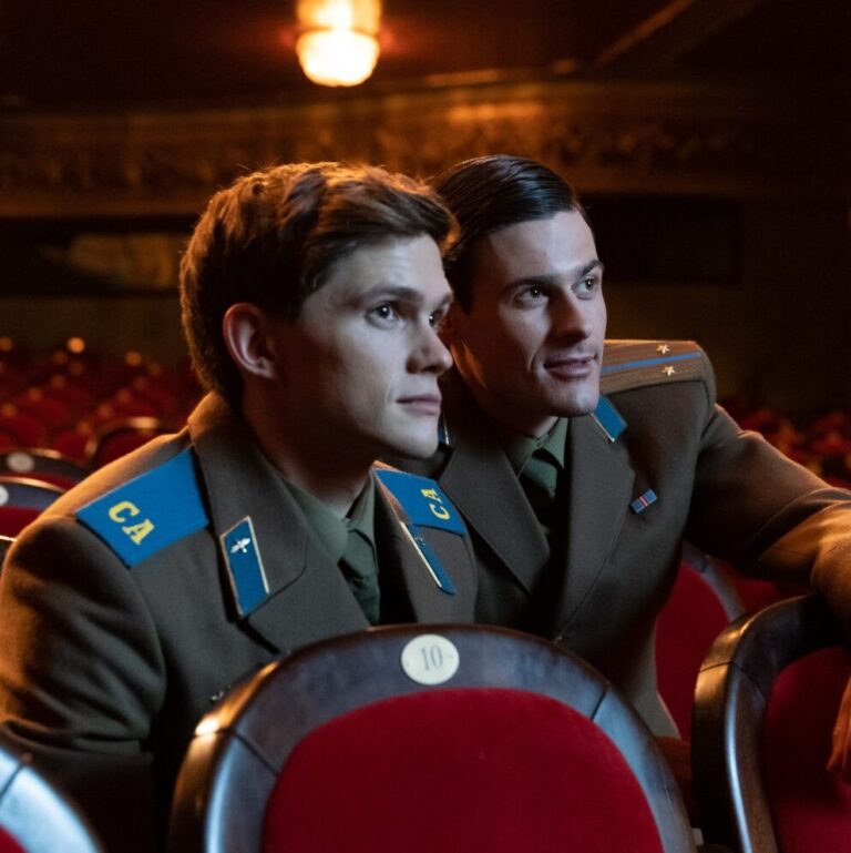 Sergey and Roman watching something at a cinema together sitting closely.