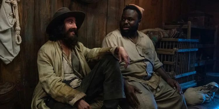 Jim and Oluwande talking and smiling sitting in their quarters close to one another.