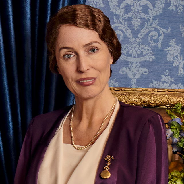 Eleanor from the series sitting in posing on a chair smiling.