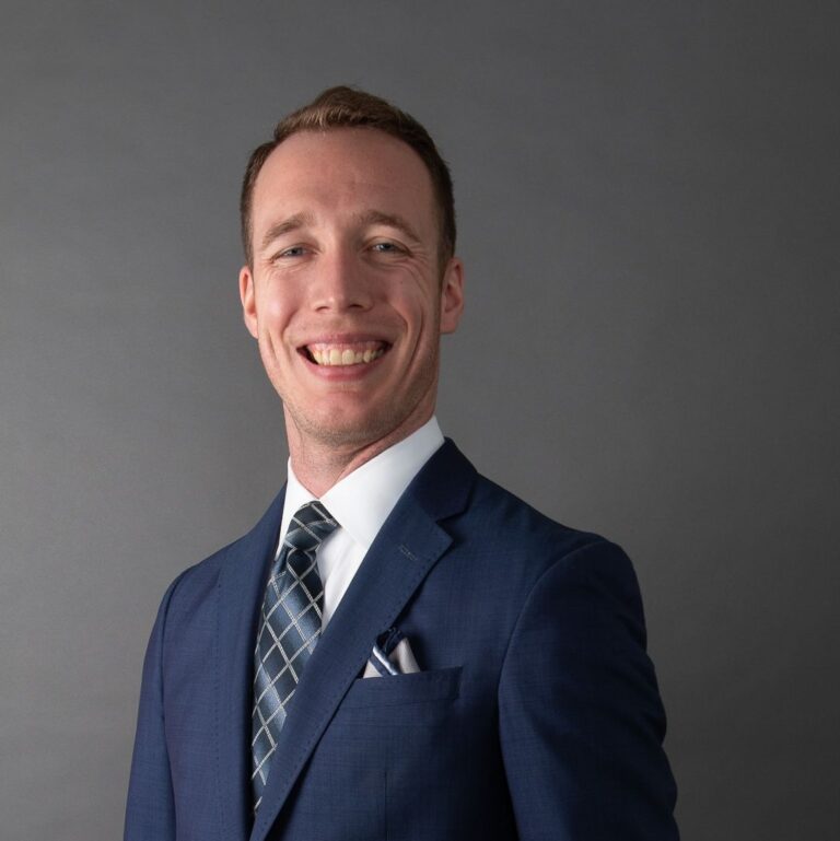 Portrait of Jared Reynolds wearing a suit and smiling.