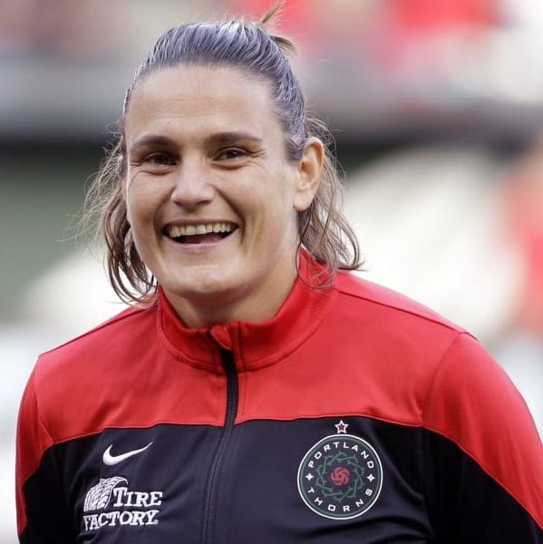 Nadine Angerer at. match smiling to the camera wearing a Portland Thorns sweater.