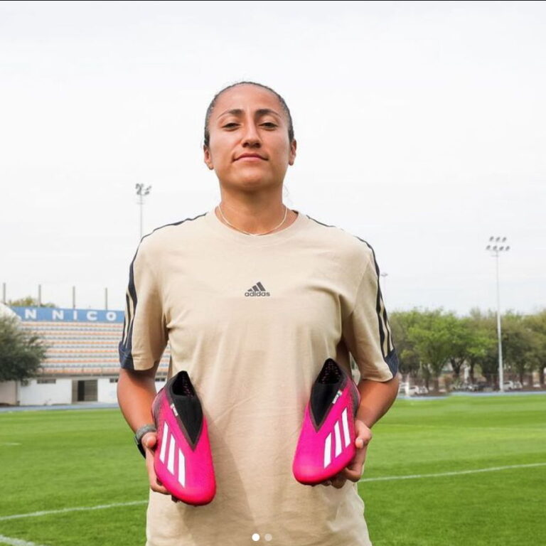 Stephanie posing with her cleats on a field.